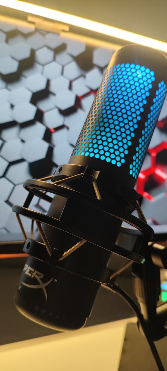 HyperX QuadCast S com iluminação azul instalado no braço articulado